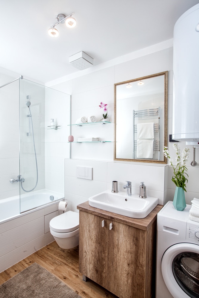 Baignoire îlot moderne : design minimaliste et ambiance spa. Baignoire îlot blanche, robinetterie minimaliste et parquet en bois clair à chevrons. Étagères intégrées décoratives dans la salle de bain moderne.